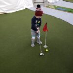 Child putting a golf ball.