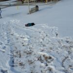 A child rolling down a snow covered hill.