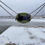 A child on a swing outdoors in the winter.