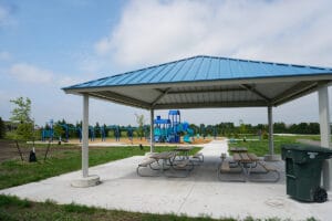 picnic shelter with four tables underneath and playground in the background at Horizon Park