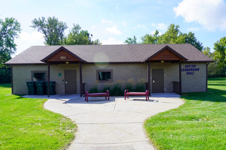 outside view of an indoor community shelter with park benches in the front