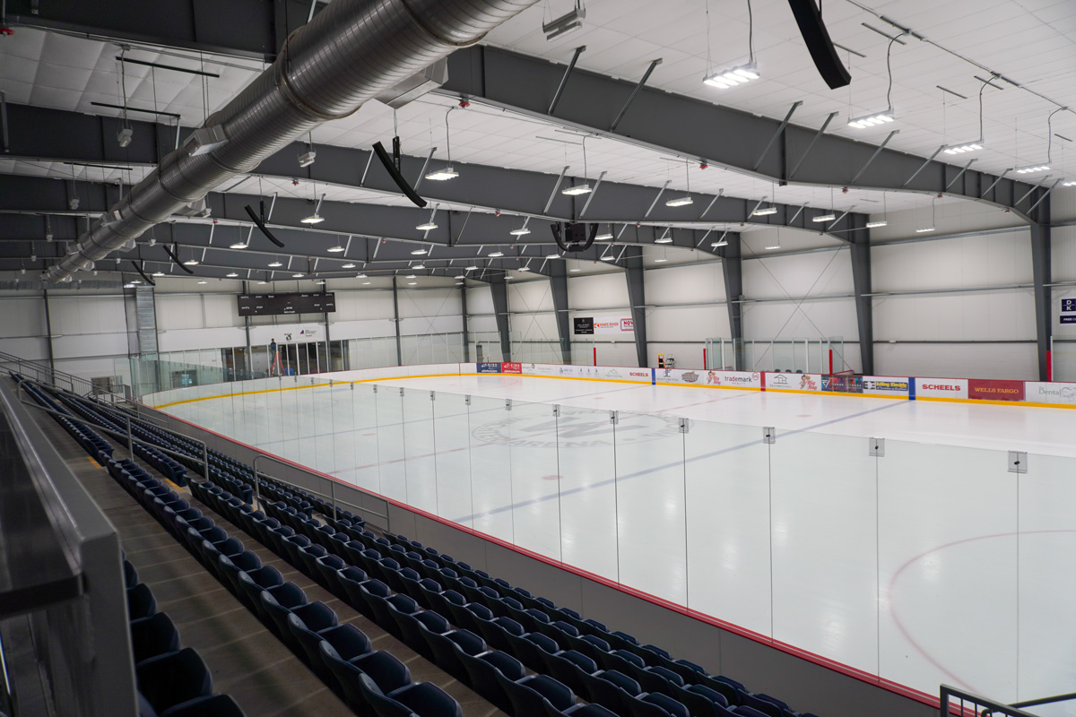 wide angle view of indoor ice arena with bleachers