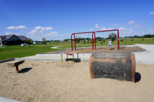 playground equipment including a climbing log and sand table at Hidden Star Park