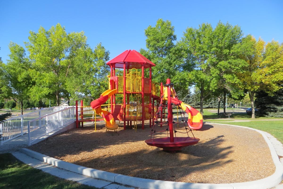 red and yellow fire station themed playground at Igoe Park with trees in the background