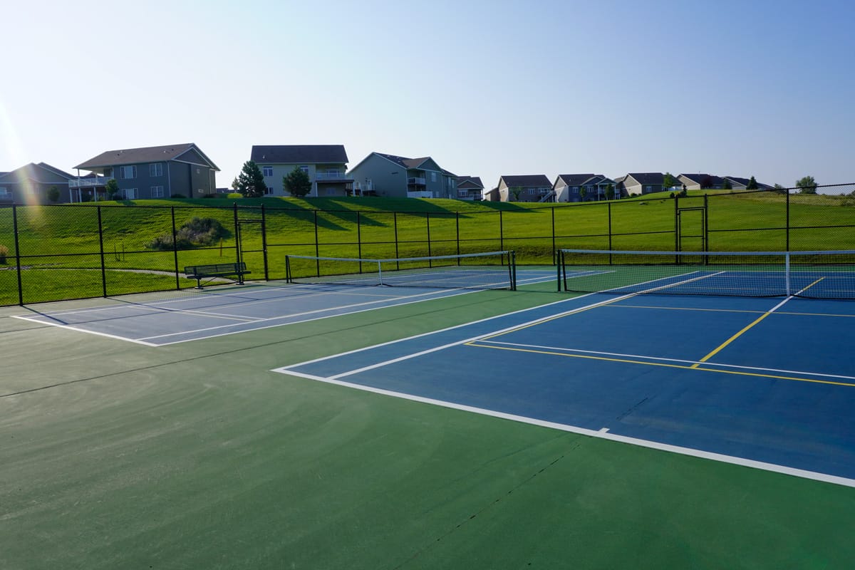 two pickleball courts at Johnny Gisi Memorial Park with houses on top of a hill in the background