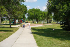 two people walking on a trail near a playground