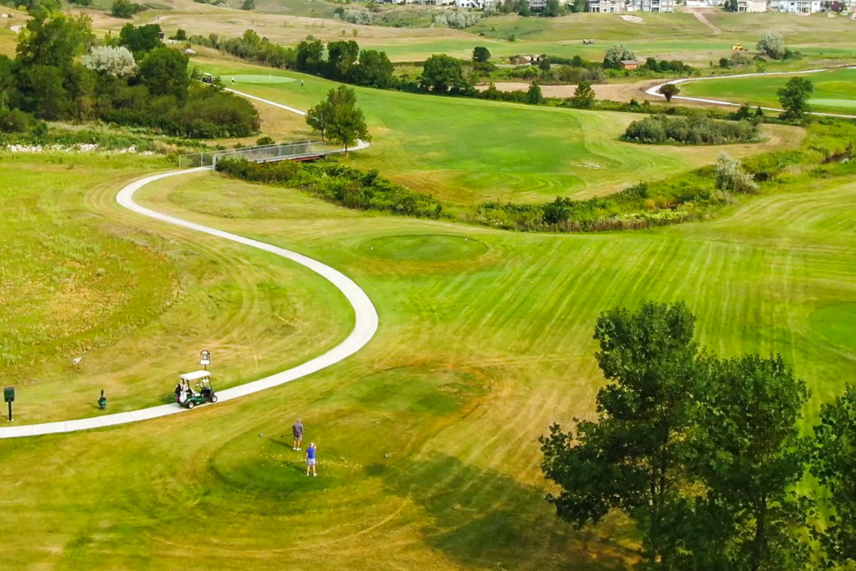 wide angle view of a golf course with a golf cart path