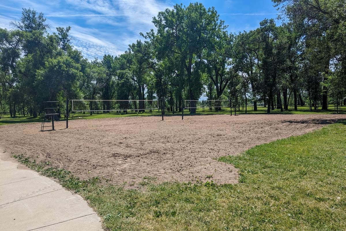 two sand volleyball courts at Pioneer Park with tall trees surrounding them