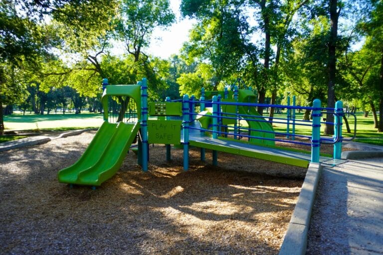 green and blue playground near shelter 11 at Sertoma Park with the words "Play It Safe!" on one side