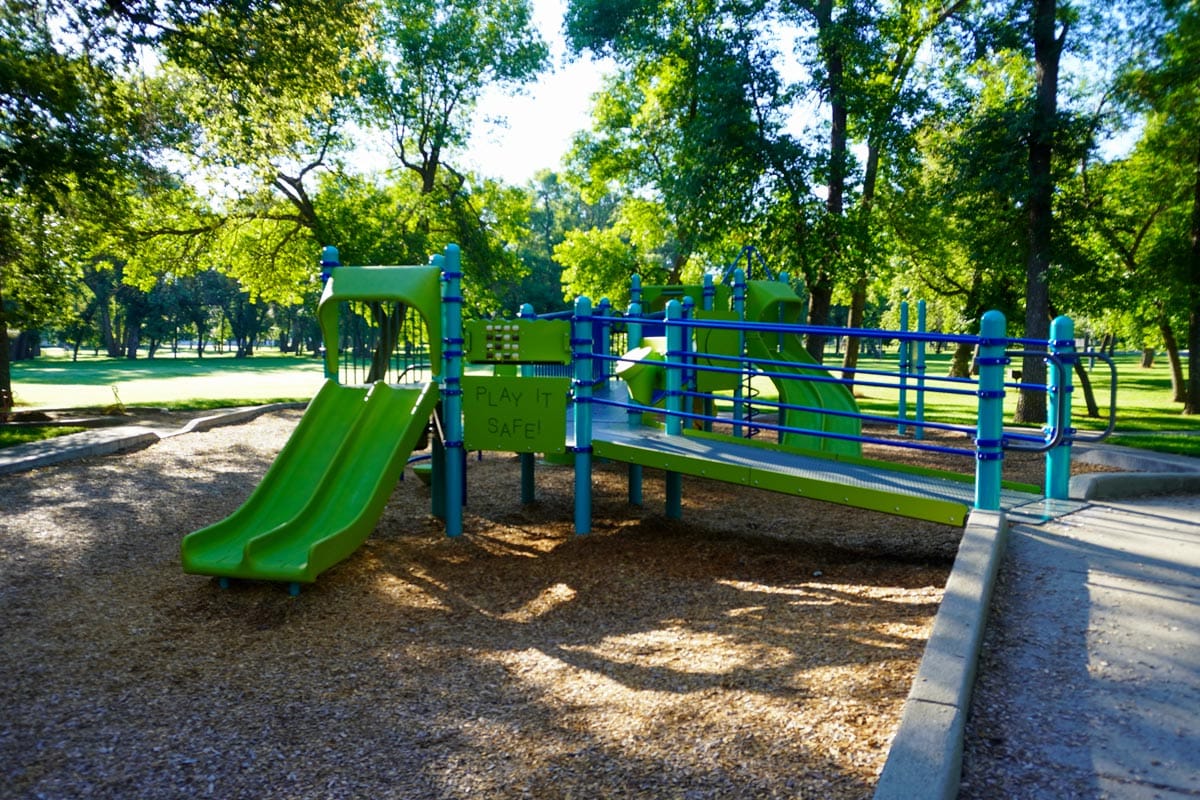 green and blue playground near shelter 11 at Sertoma Park with the words "Play It Safe!" on one side
