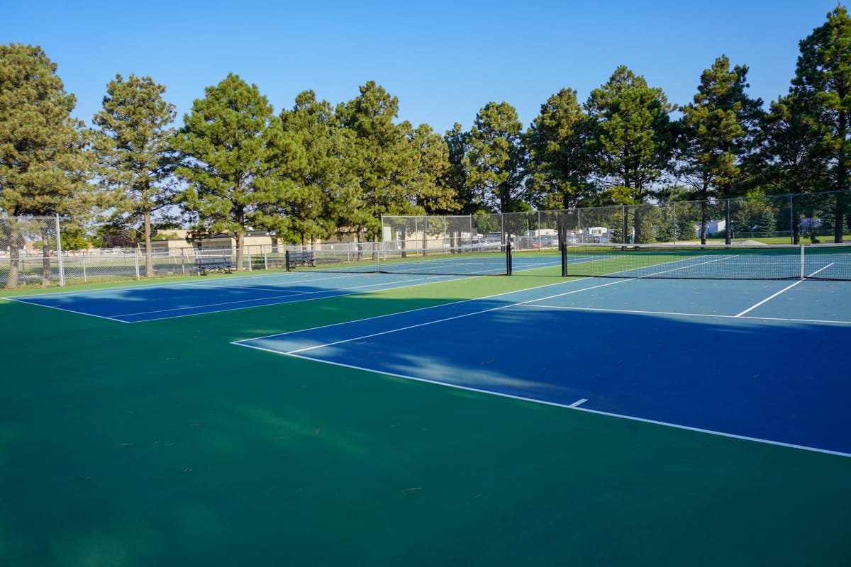 two tennis courts at Sons of Norway Park surrounded by tall trees