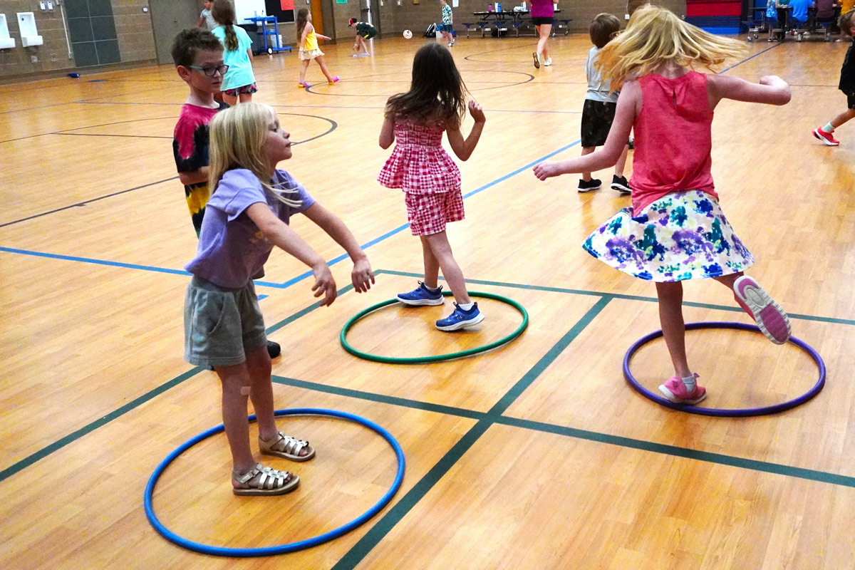kids playing in hoola hoops in a gym