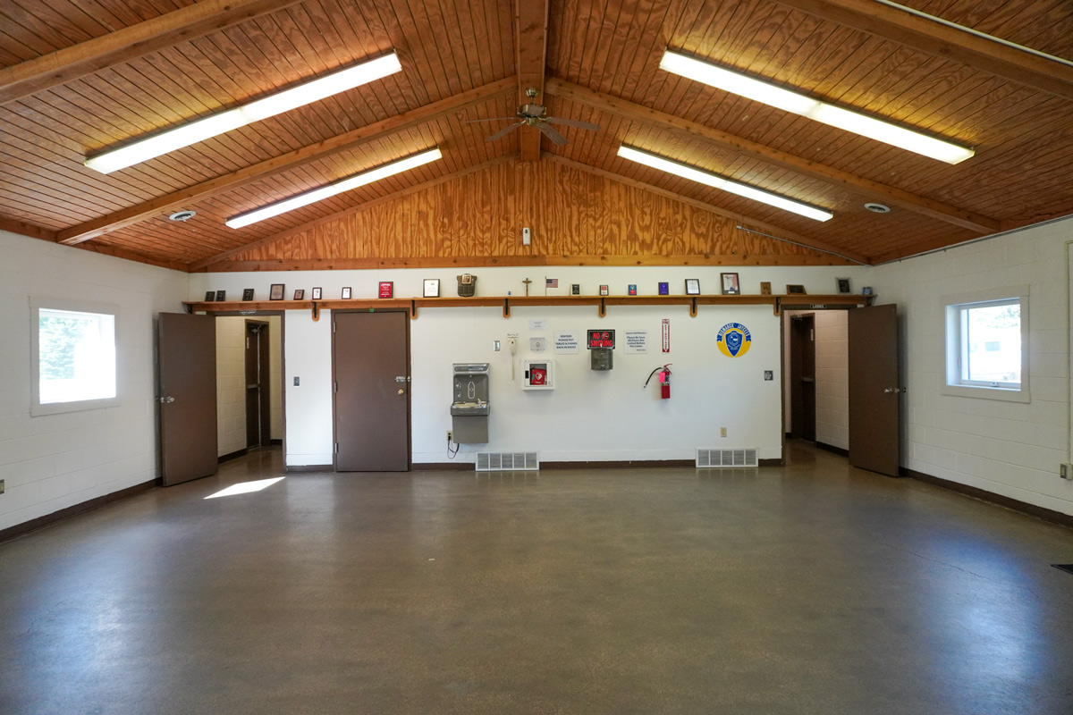 wide angle view of the interior of an indoor community shelter with a wood ceiling