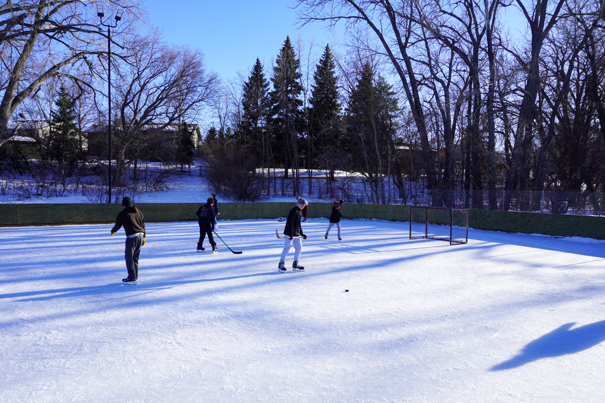 people playing hockey and skating on an outdoor rink