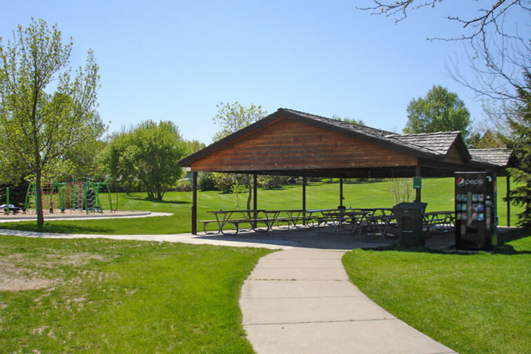 outdoor picnic shelter with picnic tables near a playground
