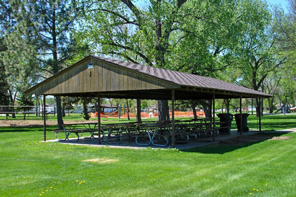 outdoor picnic shelter with picnic tables surrounded by trees