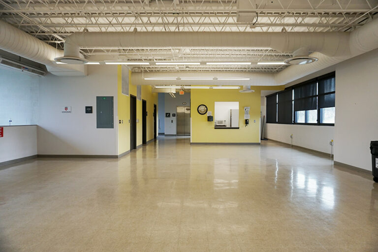 wide angle view of the interior of an indoor community center with a window to a kitchenette