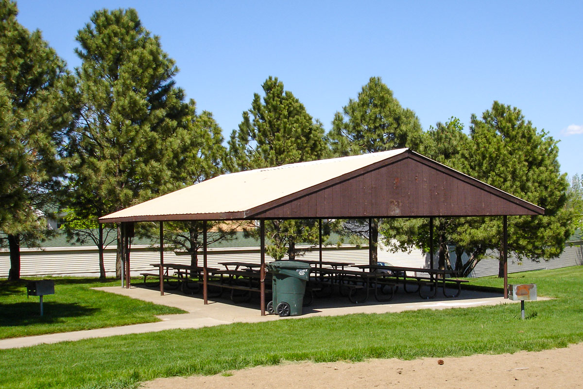 outdoor shelter with picnic tables near a sand volleyball court