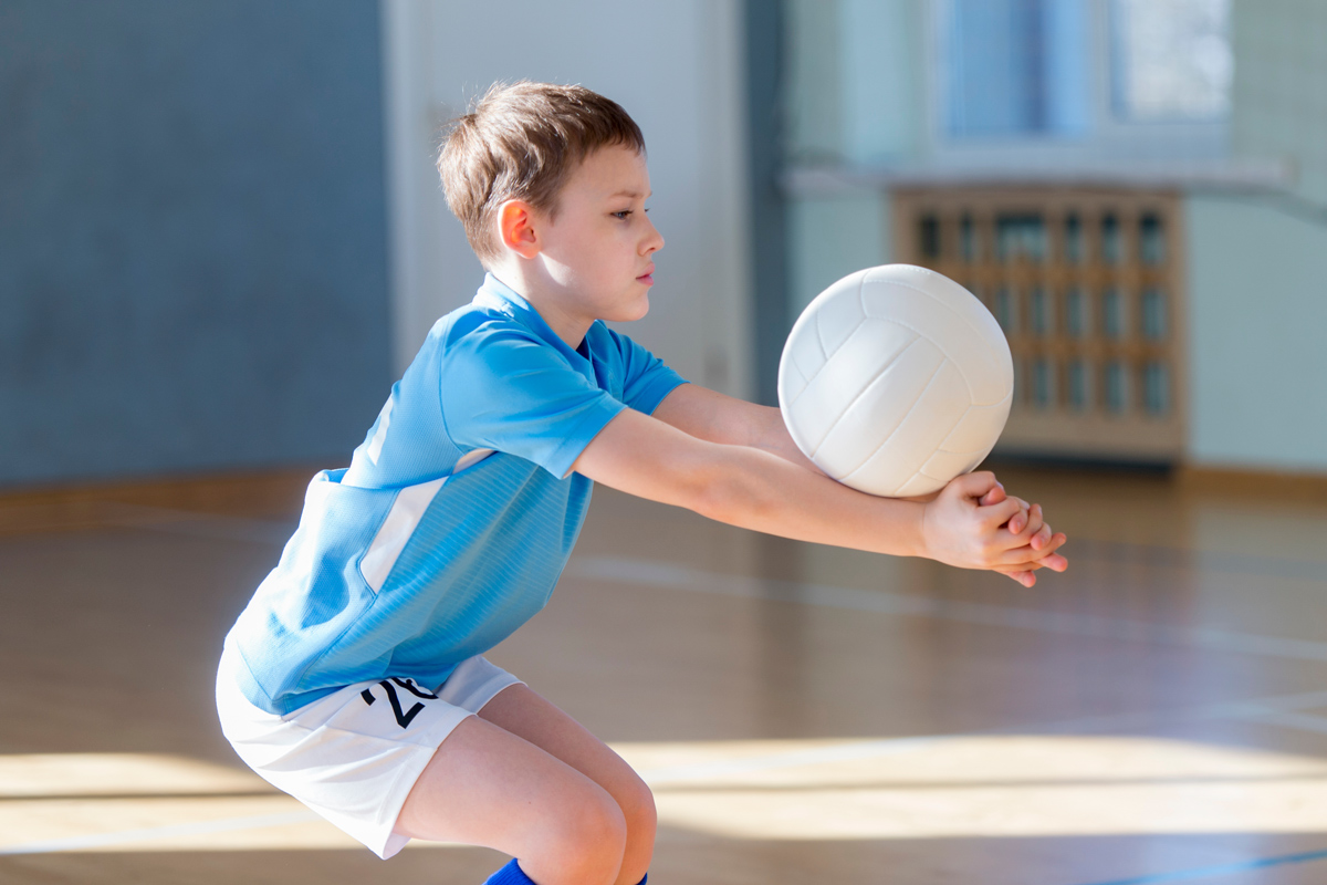 youth playing volleyball in a school gym