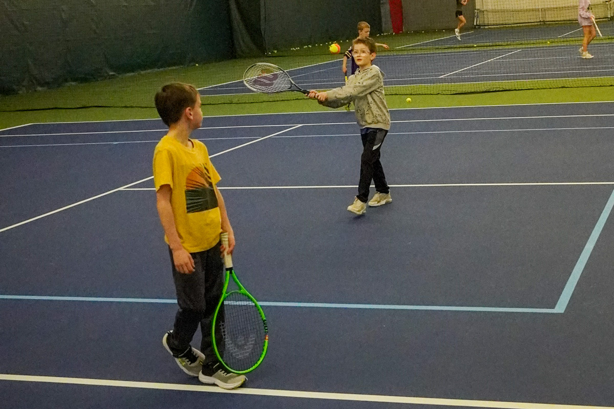 Junior-Team-Tennis-Challenge-2024 two boys playing tennis together at an indoor court