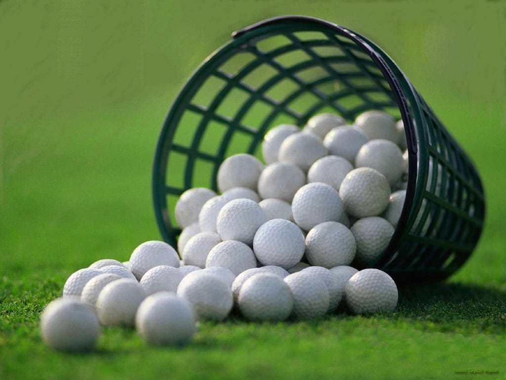Bucket of golf balls tipped over on ground