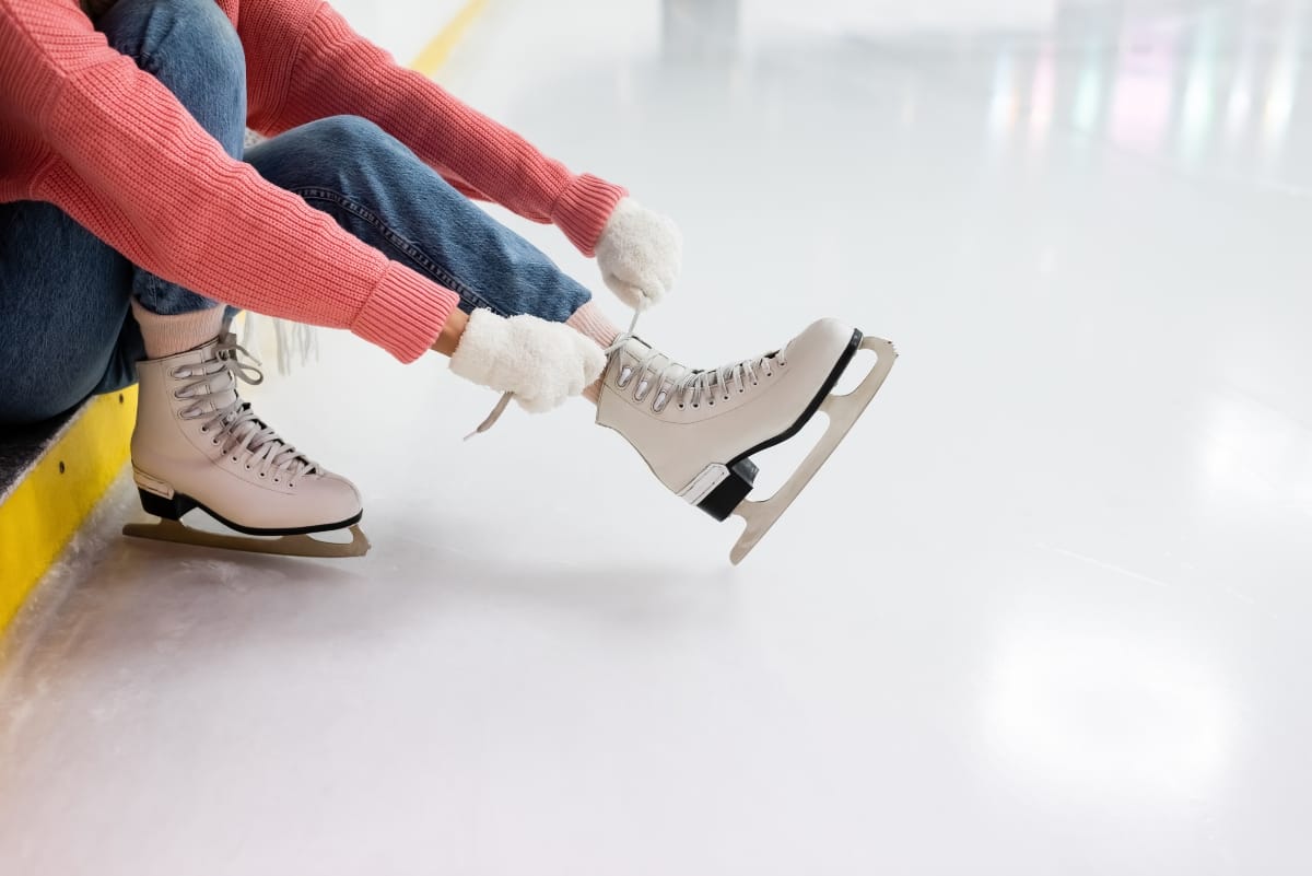 partial view of woman tying laces on ice skates