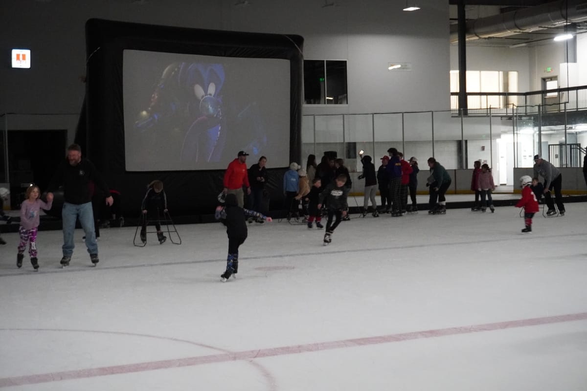 Screen showing movie set up in indoor ice arena with people skating