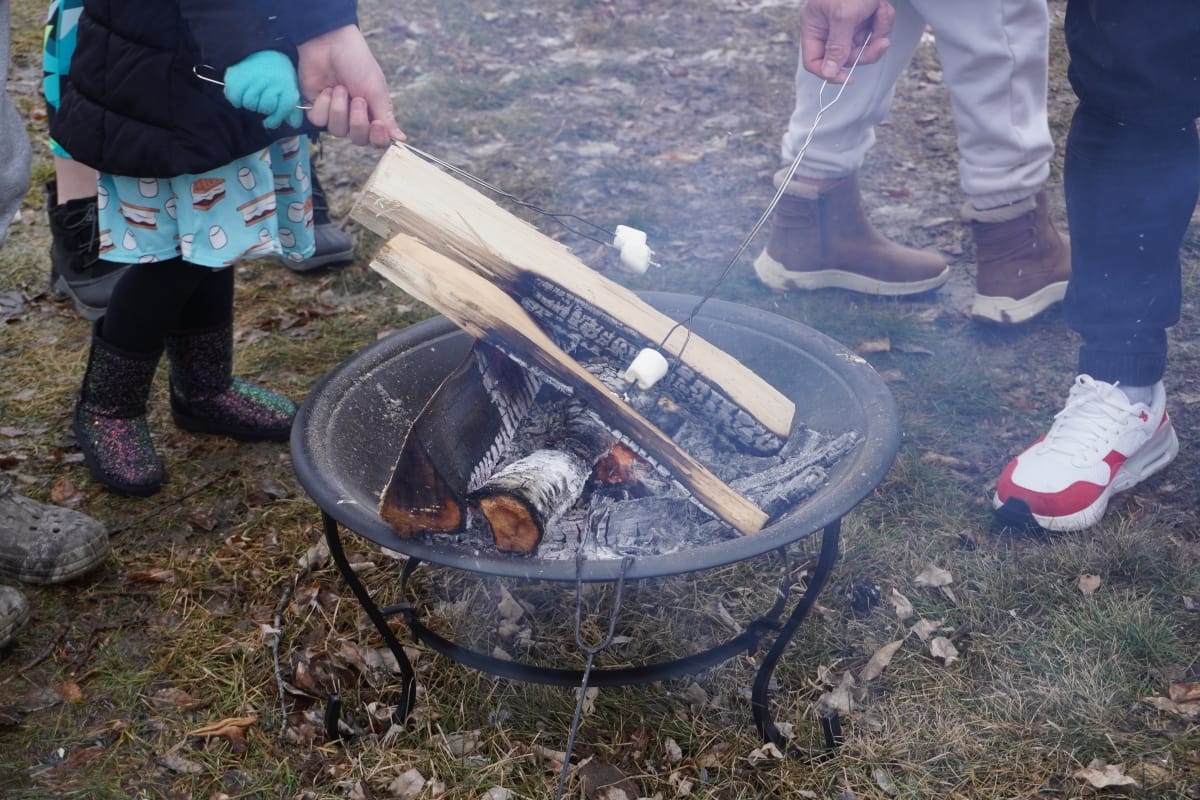Two people melting marshmallows over outdoor firepit