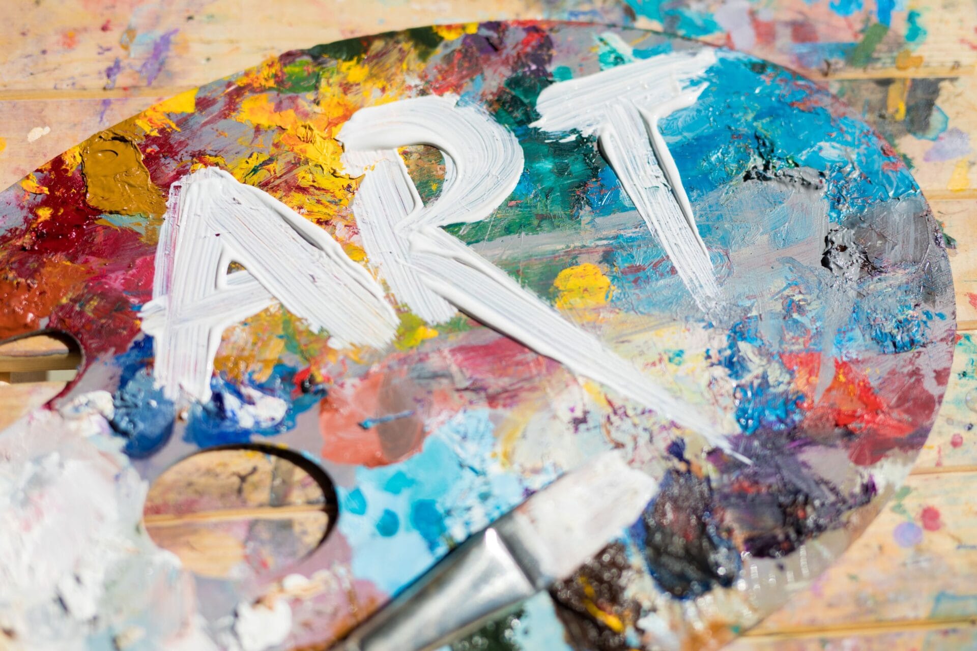 a colorful paint palette with the word "art" painted in white on it