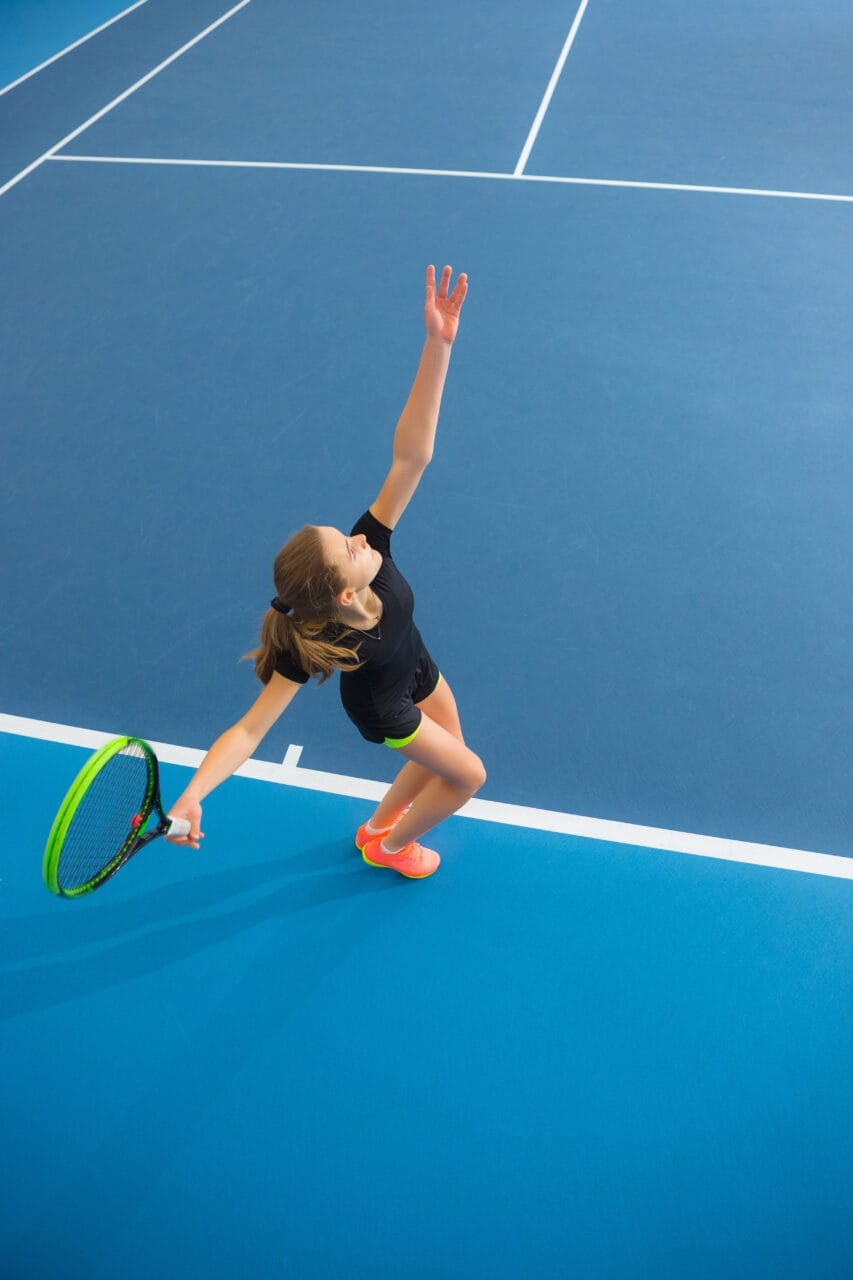 teenager prepares to hit tennis ball on a tennis court