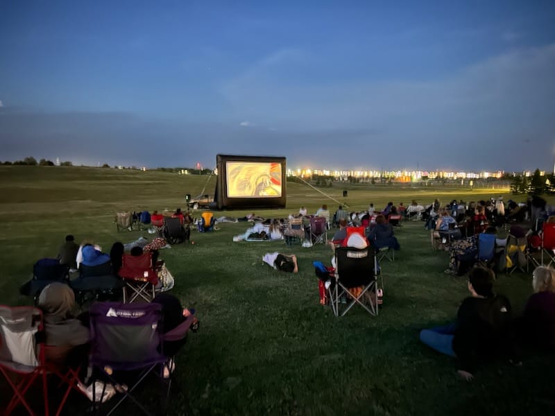 Movie in the Park 2024 people watching a movie at Movie in the Park at night
