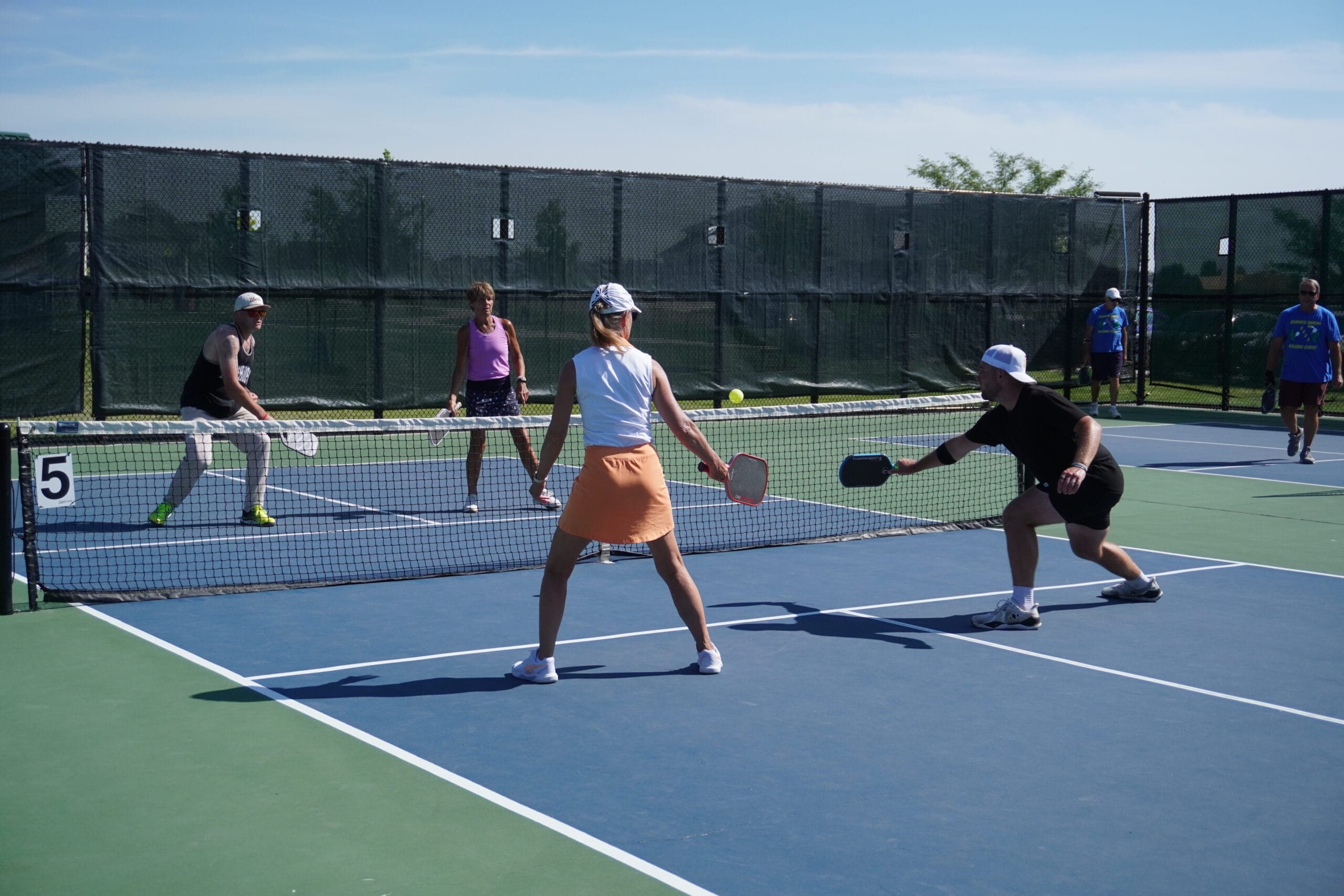 adults playing pickleball on an outdoor court