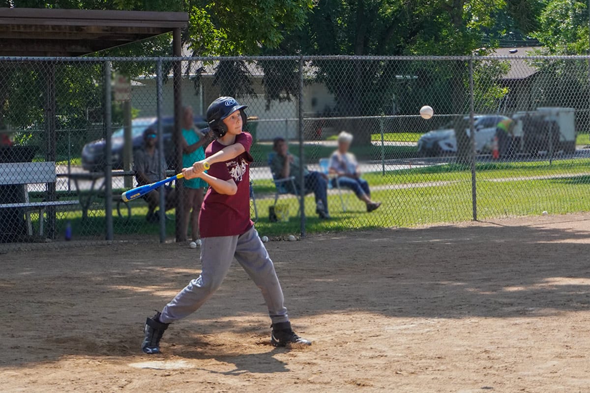 youth baseball player prepares to swing bat at a baseball at home plate