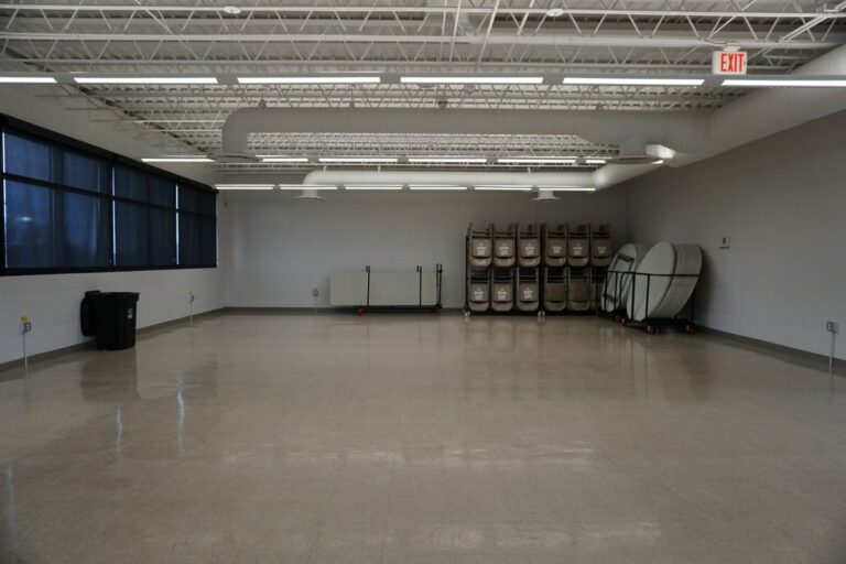 Interior view of Hillside Aquatic Complex Community Room with tables and chairs lined up against a wall.