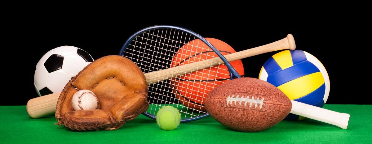 Pile of sports equipment including balls, a glove, racquet, and bat.