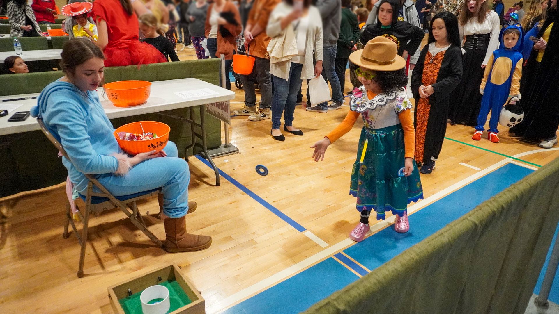 A child dressed in a Halloween costume throws a ring at the ring toss carnival booth at the Halloween Carnival.