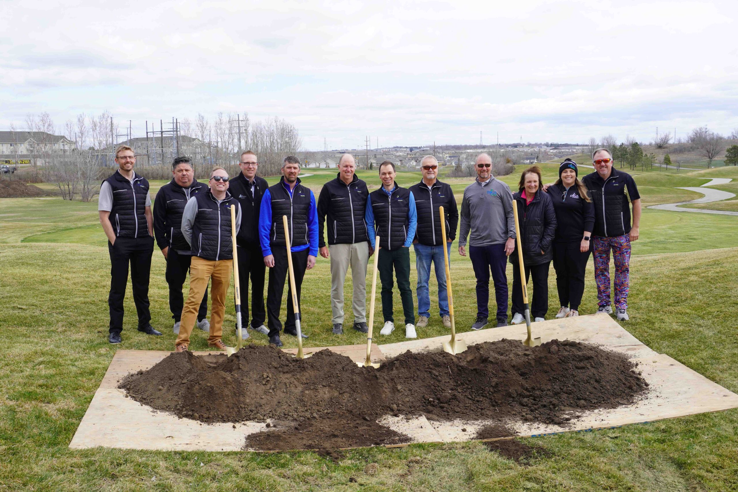 Photo of Dakota Junior Golf Association representatives at groundbreaking in front of mound of dirt with shovels